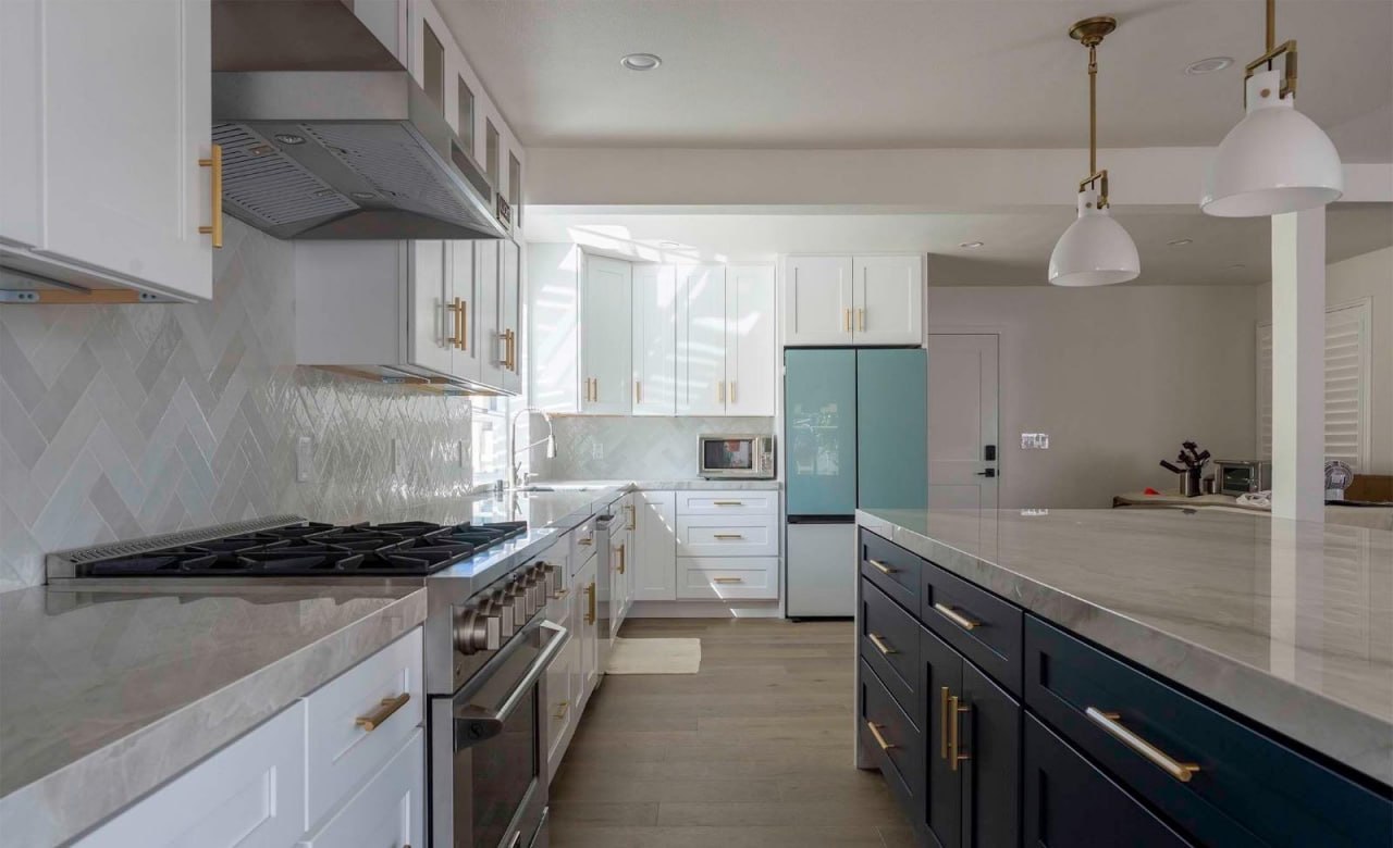 Kitchen renovation with navy island, herringbone backsplash and gold hardware by Lussoro Design + Build