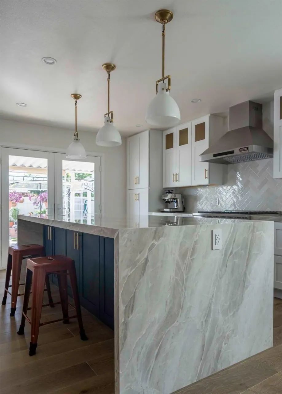 Waterfall marble island with bar seating and pendant lights by Lussoro Design + Build
