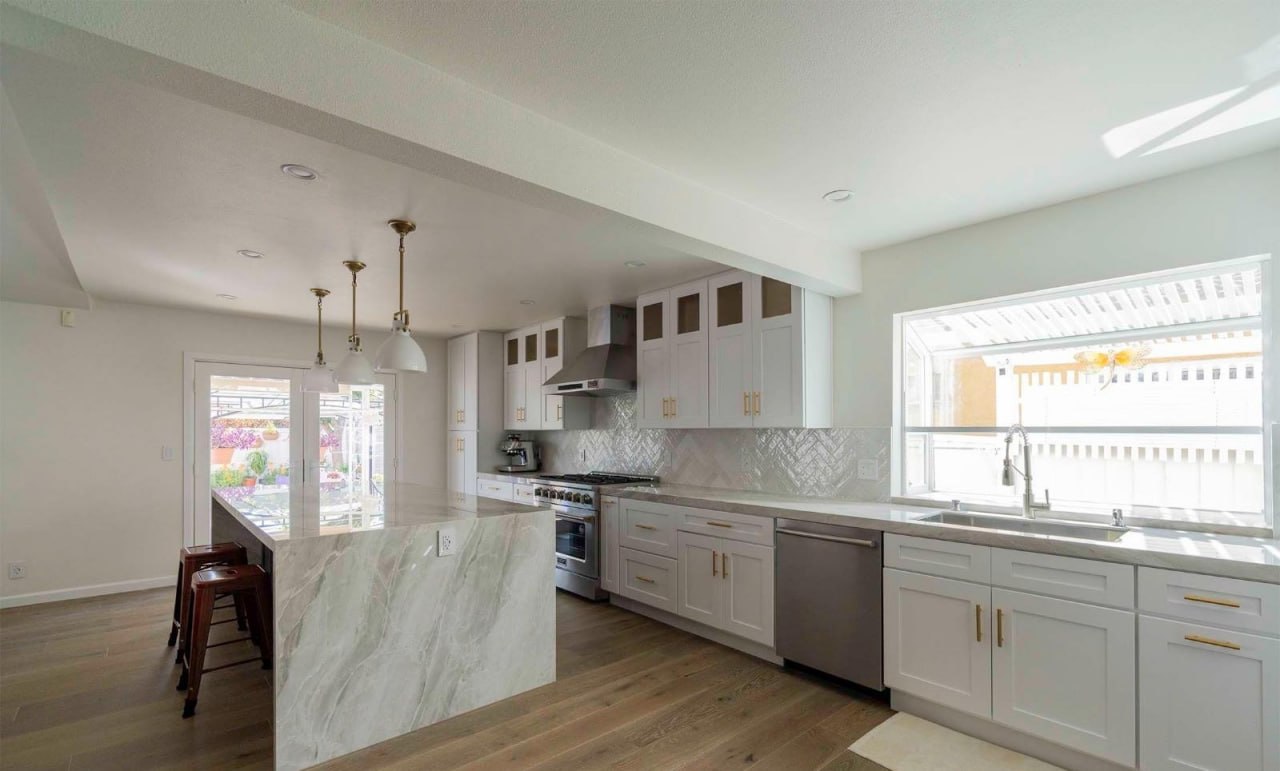 Open kitchen renovation with natural light and marble island by Lussoro Design + Build