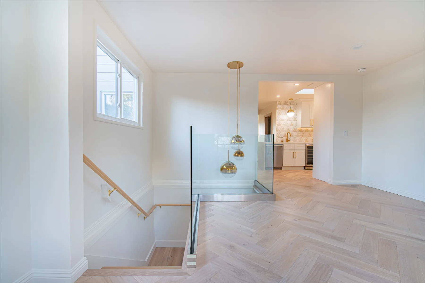 Open-plan whole-home renovation with herringbone wood floors and modern lighting by Lussoro Design + Build