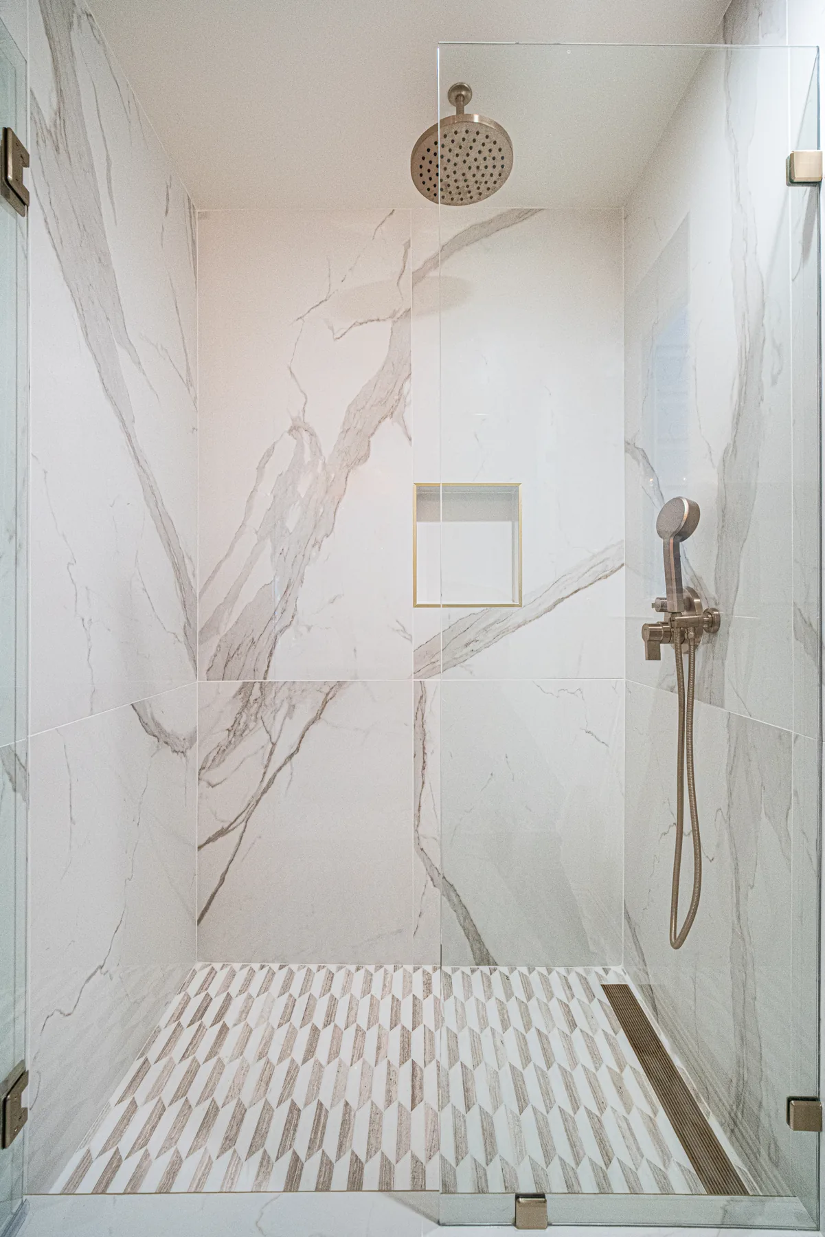 Marble-look shower with recessed wall niche by Lussoro Design + Build