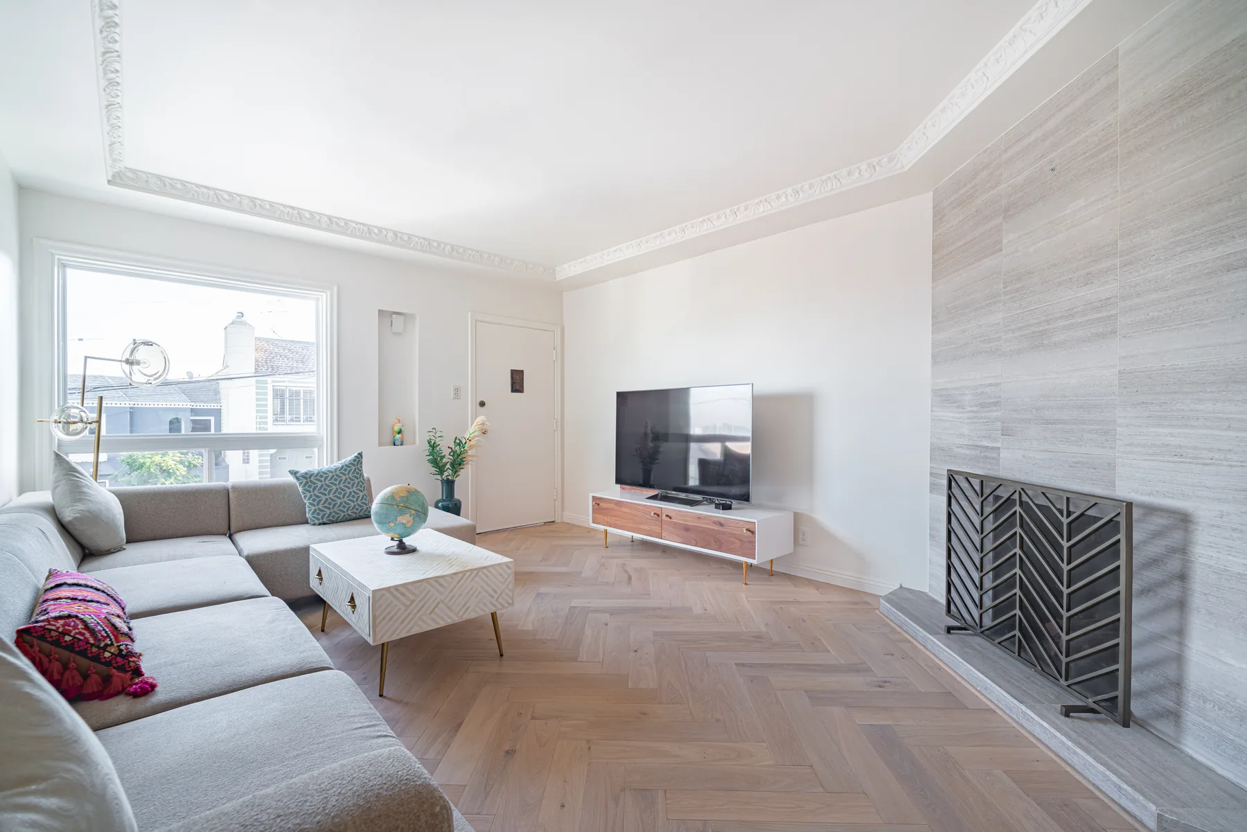 Bright living room renovation with fireplace and herringbone floors by Lussoro Design + Build
