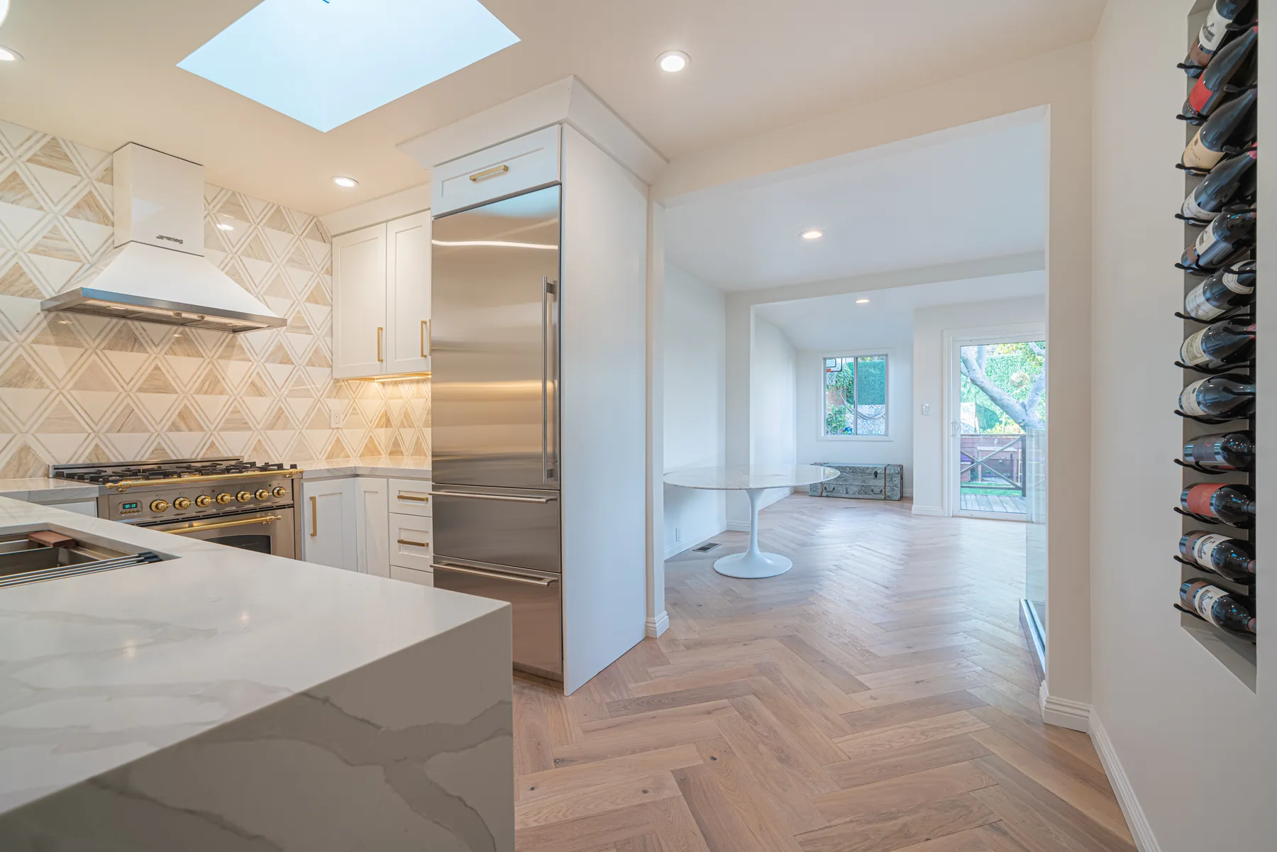 Renovated white kitchen opening to a bright living space by Lussoro Design + Build