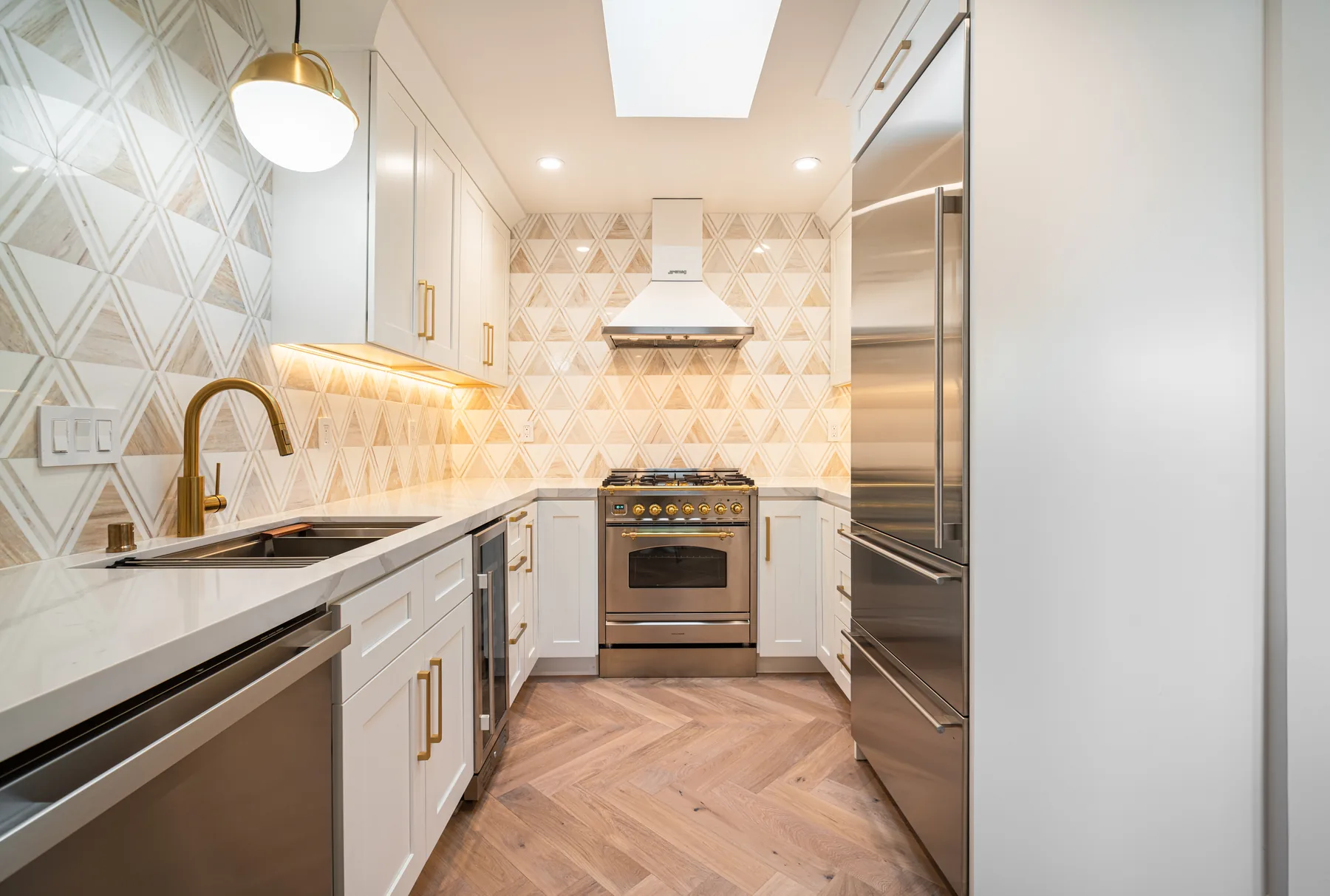 White kitchen renovation with professional range and geometric backsplash by Lussoro Design + Build