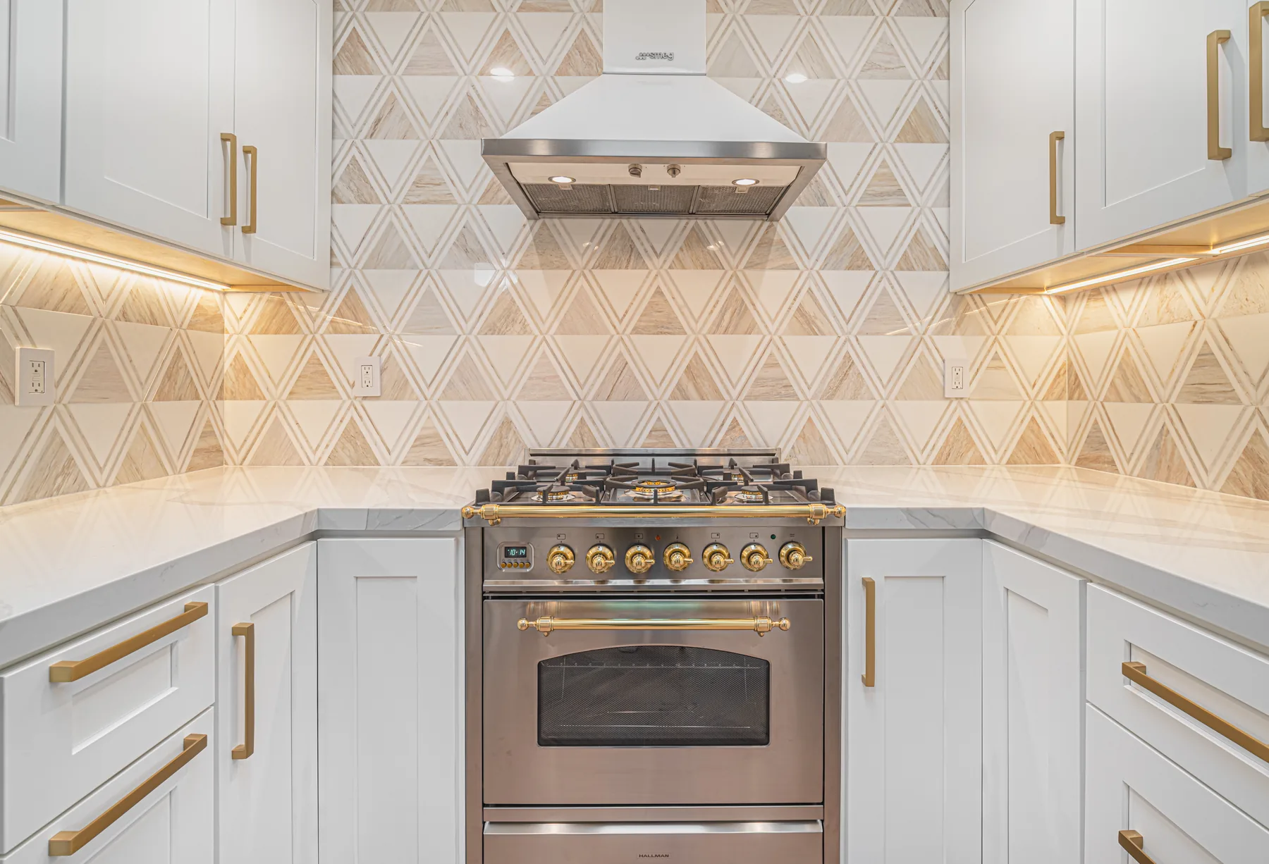 Professional range with geometric tile backsplash and brass details by Lussoro Design + Build