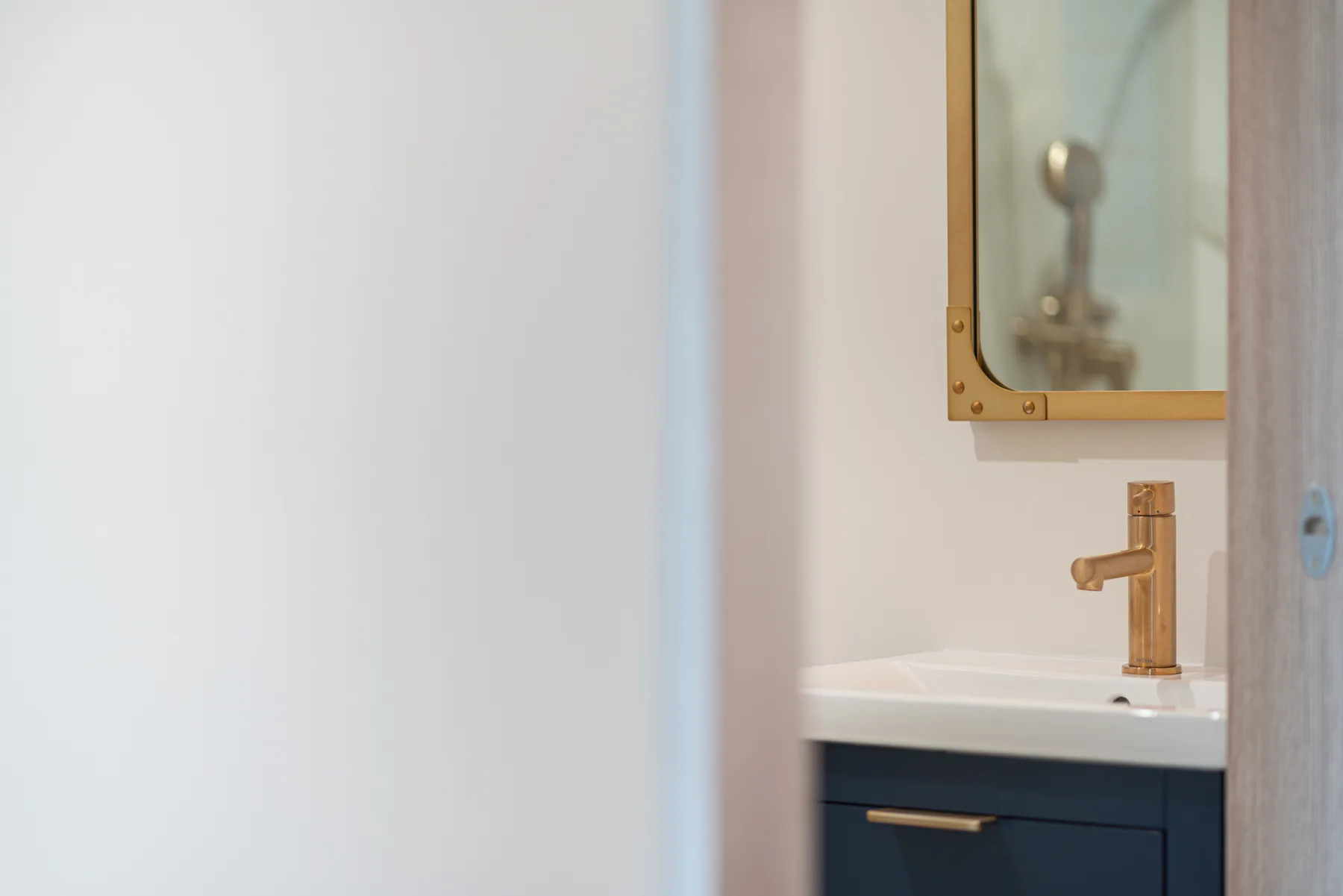 Powder room detail with navy vanity and brushed brass faucet by Lussoro Design + Build